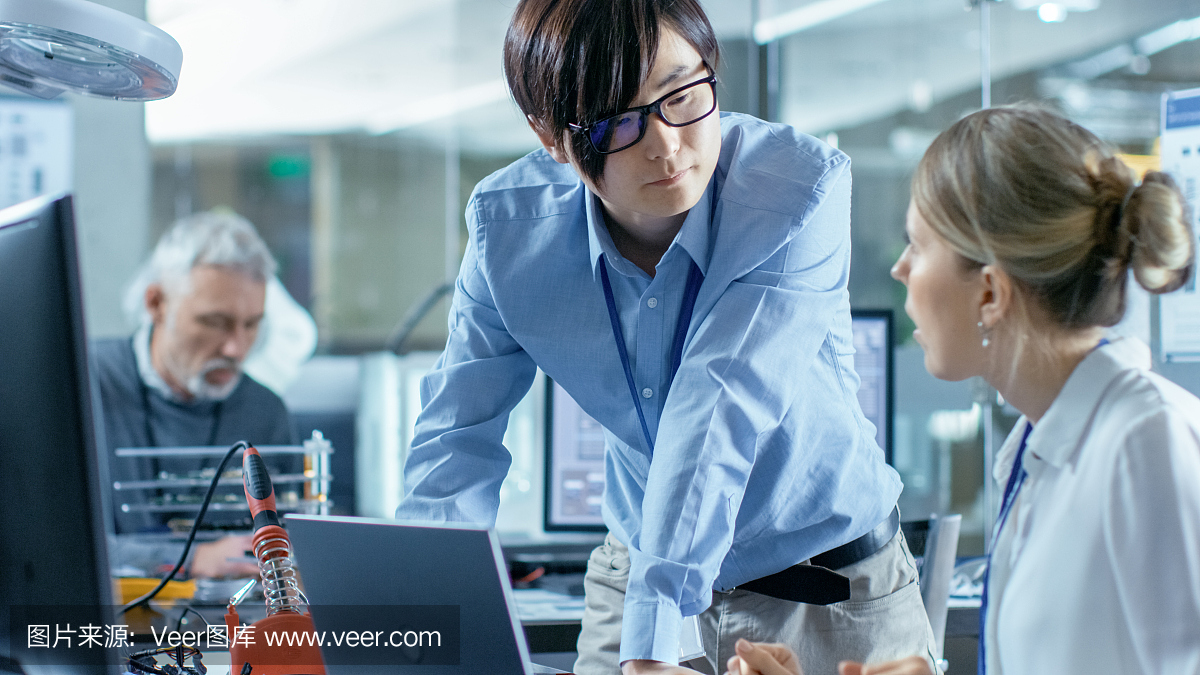 女計算機(jī)科學(xué)家用綠色屏幕模型連接電路板到她的筆記本電腦。她在先進(jìn)技術(shù)實驗室工作。